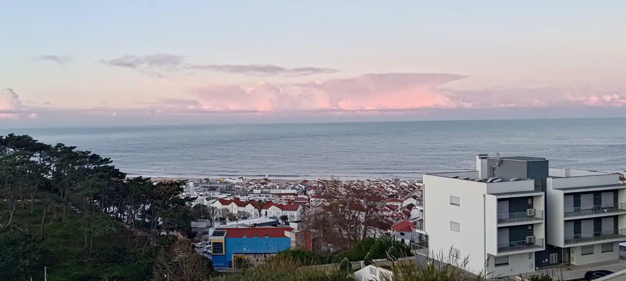 Pink sunset over Nazaré rooftops and the Atlantic