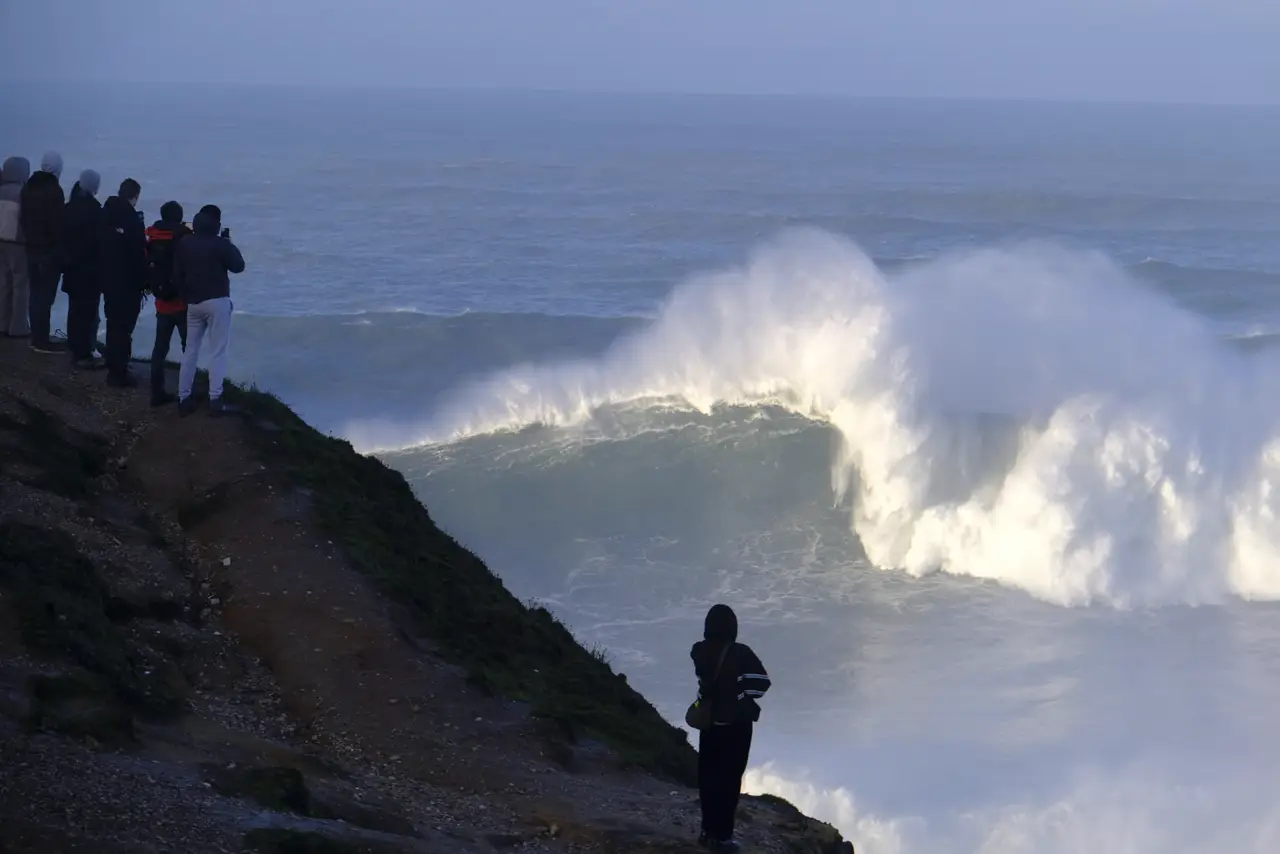 Crowds on the Nazaré cliff watching a giant wave break