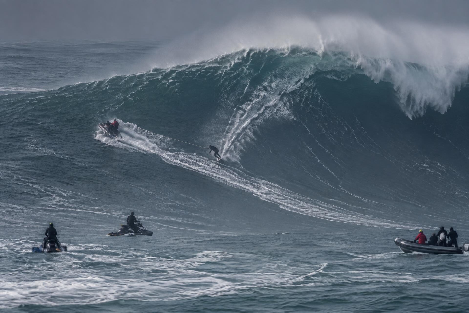 Jet ski towing a surfer into a giant wave at Praia do Norte during a big-wave event